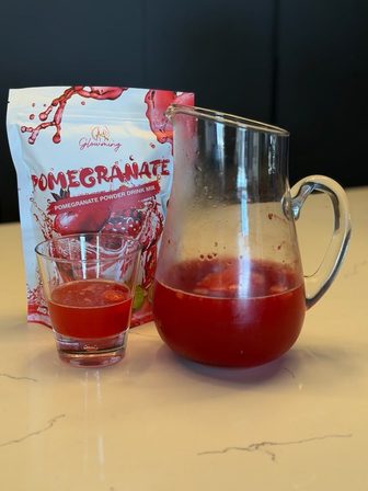A Pomegranate pouch beside a jug and a glass of Pomegranate Glowming